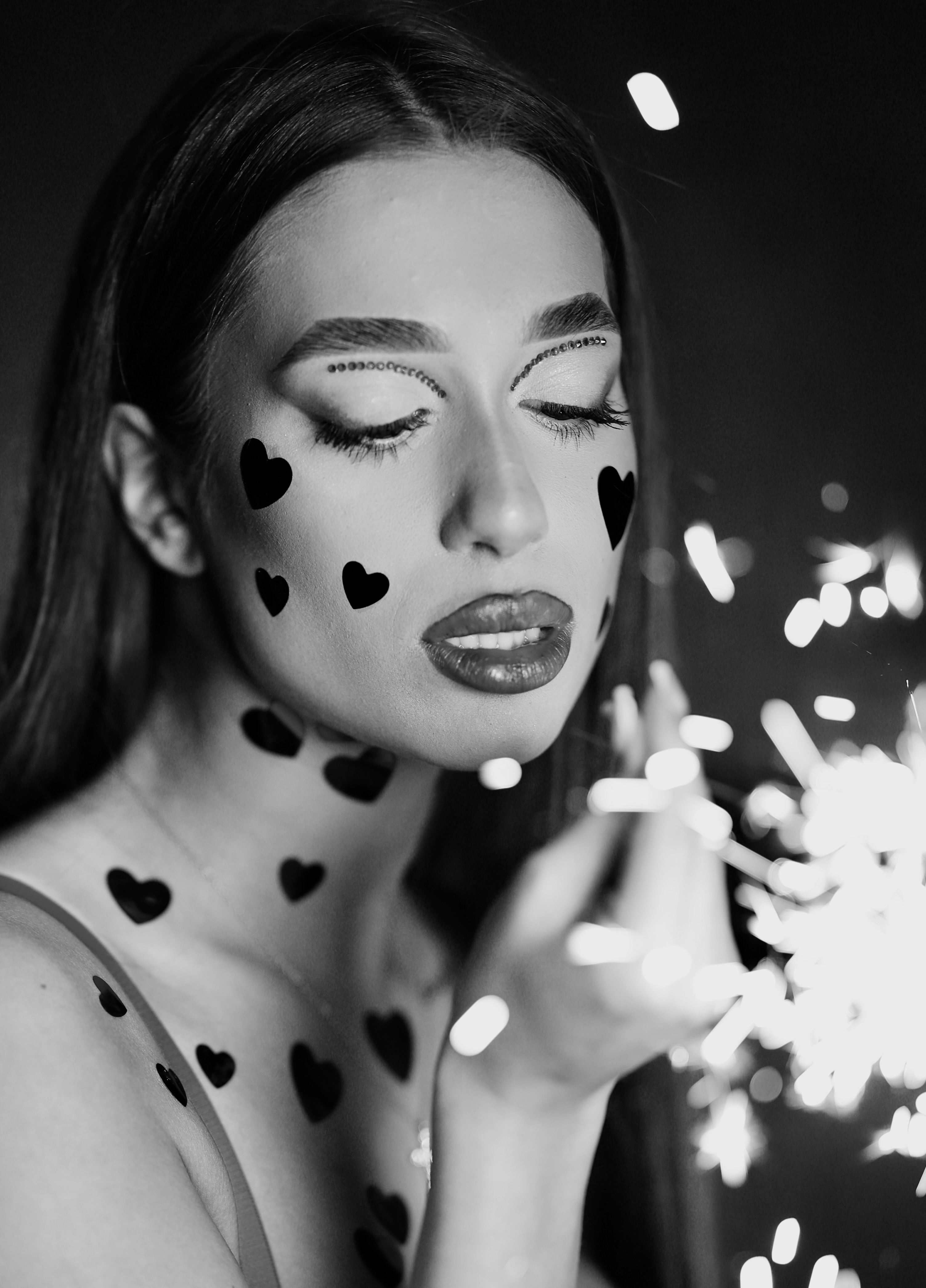 Beauty portrait with heart confetti and sparkler, eyes closed